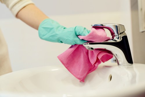 Professional short-let cleaner sanitising kitchen and bathroom surfaces